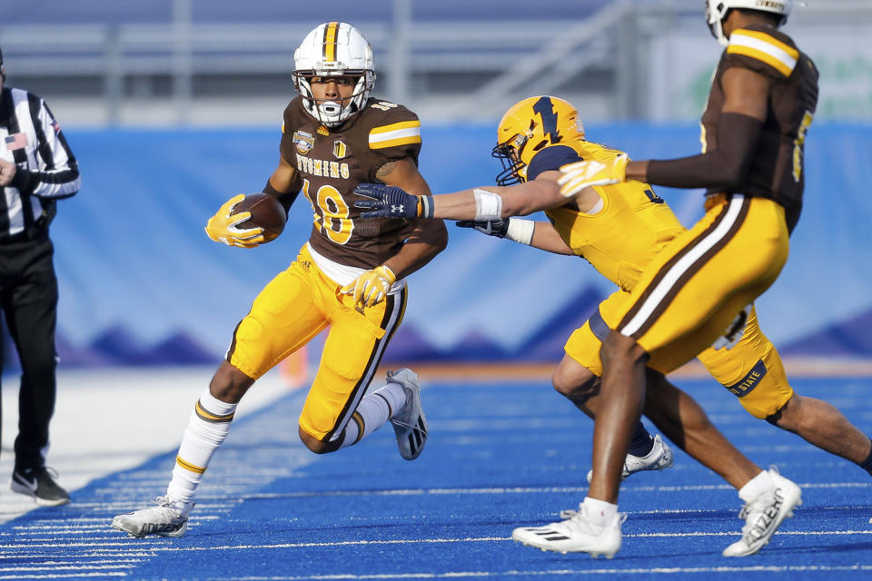 Wyoming wide receiver Joshua Cobbs (18) turns up the sidelines after a reception as Kent State safety Dean Clark (3) pushes him out of bounds during the first half of the Idaho Potato Bowl NCAA college football game, Tuesday, Dec. 21, 2021, in Boise, Idaho. (AP Photo/Steve Conner)