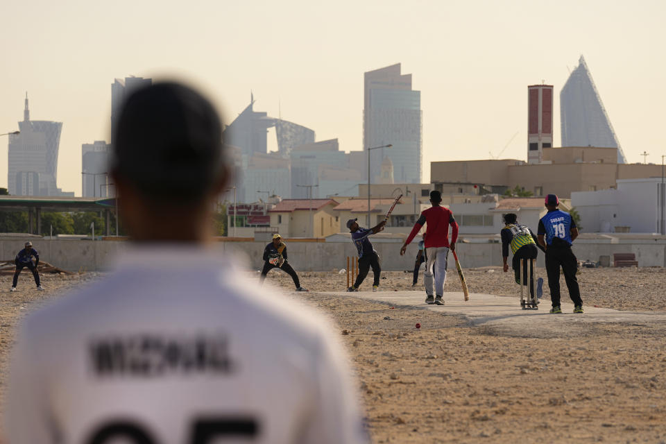 People play cricket in the streets in Doha, Qatar, Friday, Nov. 25, 2022. As dawn broke Friday as Qatar hosts the World Cup, the laborers who built this energy-rich country's stadiums, roads and rail filled empty stretches of asphalt and sandlots to play cricket. (AP Photo/Abbie Parr)