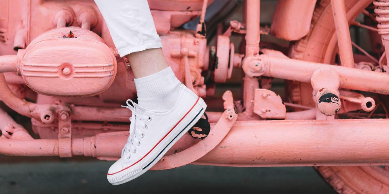 woman in white sneakers on pink painted motorcycle