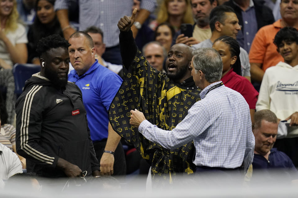 A fan, at center, gets removed from his seat after attempting to get a haircut during the quarterfinals of the U.S. Open tennis championships between Nick Kyrgios, of Australia, and Karen Khachanov, of Russia, Tuesday, Sept. 6, 2022, in New York. (AP Photo/Charles Krupa)