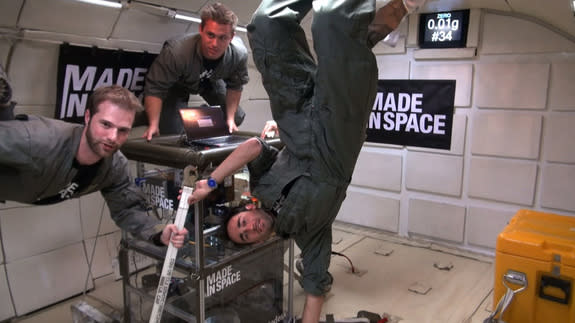 Made in Space team members with their 3-D printer hang on during a zero-g test flight.