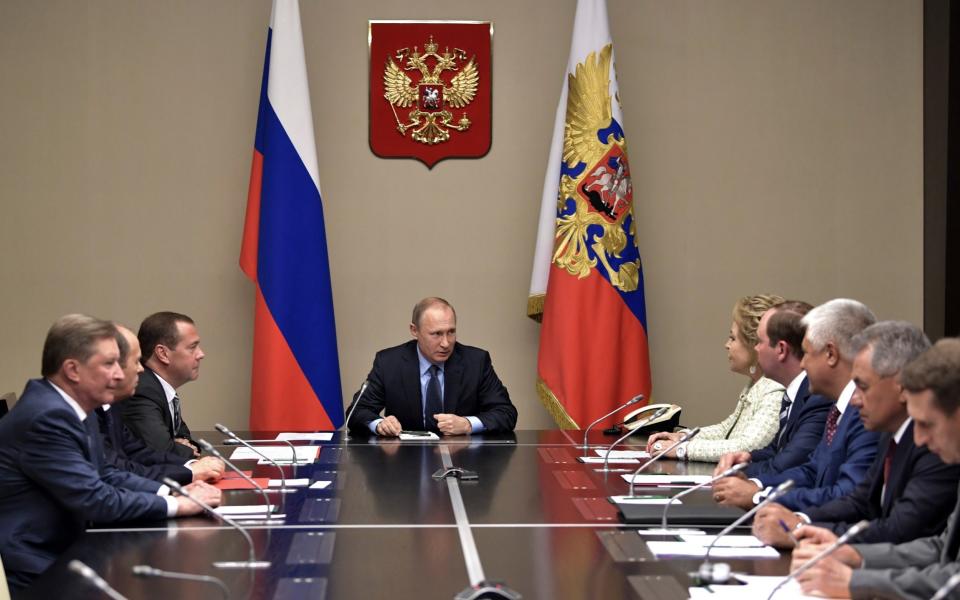 Vladimir Putin, centre, chairs a meeting at the Novo-Ogaryovo residence outside Moscow, Russia, on Friday - Credit: AP