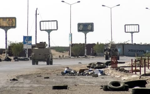 Armoured vehicles of the Yemeni pro-government forces are seen driving past destruction in an industrial district in the eastern outskirts of the port city of Hodeidah  - Credit: AFP