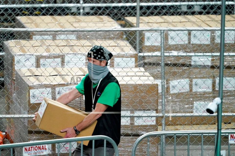 Maricopa County ballots cast in the 2020 general election are fenced in a secure area as a box is delivered to be examined and recounted by contractors working for Florida-based company, Cyber Ninjas, Thursday, May 6, 2021, at Veterans Memorial Coliseum in Phoenix. The audit, ordered by the Arizona Senate, has the U.S. Department of Justice saying it is concerned about ballot security and potential voter intimidation arising from the unprecedented private recount of the 2020 presidential election results. (AP Photo/Matt York, Pool)