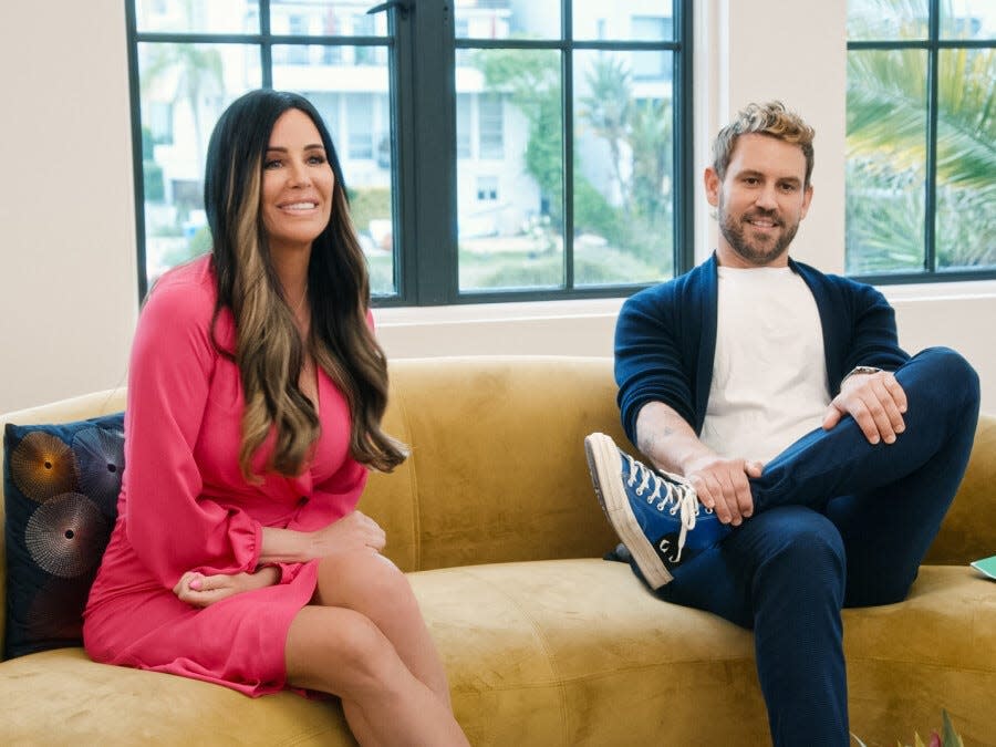 Patti Stanger and Nick Viall sitting on a couch.
