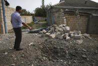 A man points to a crater that was allegedly caused by shelling during fighting over the breakaway region of Nagorno-Karabakh, in Tartar region, Azerbaijan, Wednesday, Sept. 30, 2020. Leaders of Azerbaijan and Armenia brushed off the suggestion of peace talks Tuesday, accusing each other of obstructing negotiations over the separatist territory of Nagorno-Karabakh, with dozens killed and injured in three days of heavy fighting. (AP Photo/Aziz Karimov)