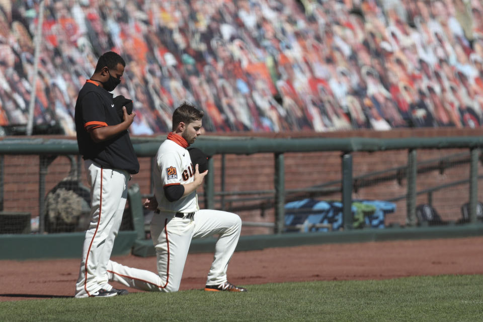 San Francisco Giants' Austin Slater, right, kneels next to teammate Wandy Peralta during the national anthem before a baseball game against the Colorado Rockies in San Francisco, Thursday, Sept. 24, 2020. (AP Photo/Jed Jacobsohn)