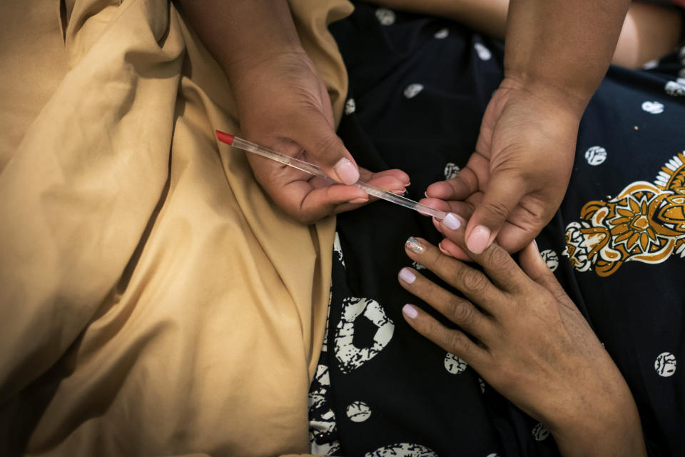 Jessica Guthrie cleans the fingernails of her mother, Constance, as part of her morning routine, in Fredericksburg, Va., on Tuesday, Sept. 20, 2022. In the 1990s, Constance made the difficult decision to move and close her beloved hair salon. She bought a home in Fredericksburg so her daughter could attend the best schools, and later became a paraprofessional in the local school district, which allowed her to have a schedule where she never missed oratorical contests or choir recitals. (AP Photo/Wong Maye-E)