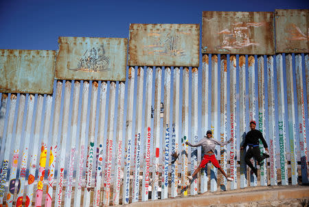 FILE PHOTO: Cristian Joel Morales (L) and Victor David Reyes Madrid, migrants from Honduras, part of a caravan of thousands traveling from Central America en route to the United States, pose in front of the border wall between the U.S. and Mexico in Tijuana, Mexico, November 23, 2018. REUTERS/Kim Kyung-Hoon
