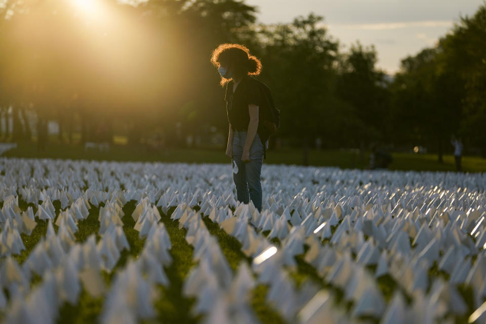 Zoe Nassimoff, of Argentina, looks at white flags that are part of artist Suzanne Brennan Firstenberg's temporary art installation, "In America: Remember," in remembrance of Americans who have died of COVID-19, on the National Mall in Washington, Friday, Sept. 17, 2021. Nassimoff's grandparent who lived in Florida died from COVID-19. (AP Photo/Brynn Anderson)