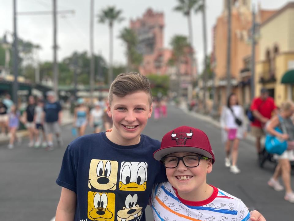 kari's boys posing for a photo on hollywood boulevard at hollywood studios with tower of terror in the background