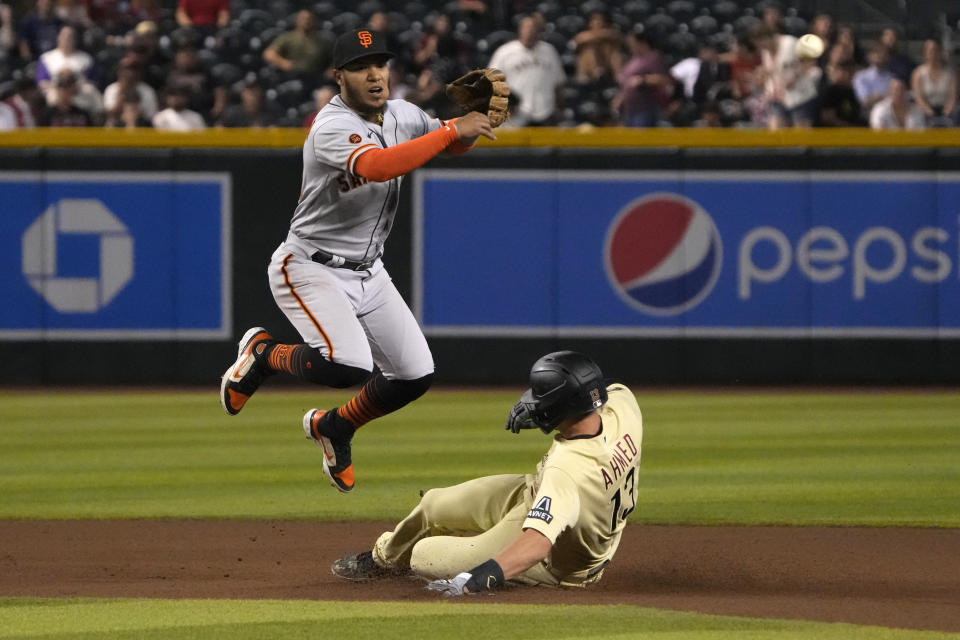 San Francisco Giants second baseman Thairo Estrada, top, turns a double play while avoiding Arizona Diamondbacks' Nick Ahmed (13) on a ball hit by Gabriel Moreno in the fourth inning during a baseball game, Friday, May 12, 2023, in Phoenix. (AP Photo/Rick Scuteri)