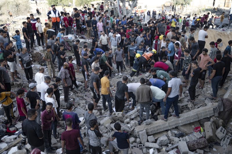 <cite>2023年10月16日，以色列空襲加薩走廊汗尤尼斯後，巴勒斯坦民眾在斷垣殘瓦中尋找倖存者。（美聯社）</cite>
