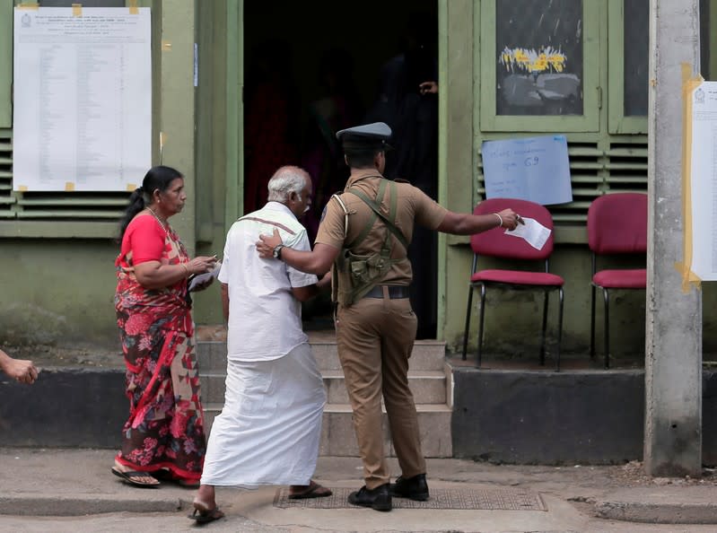 A police officer directs a man to a line at a polling station as he arrives to cast his vote during the presidential election in Colombo