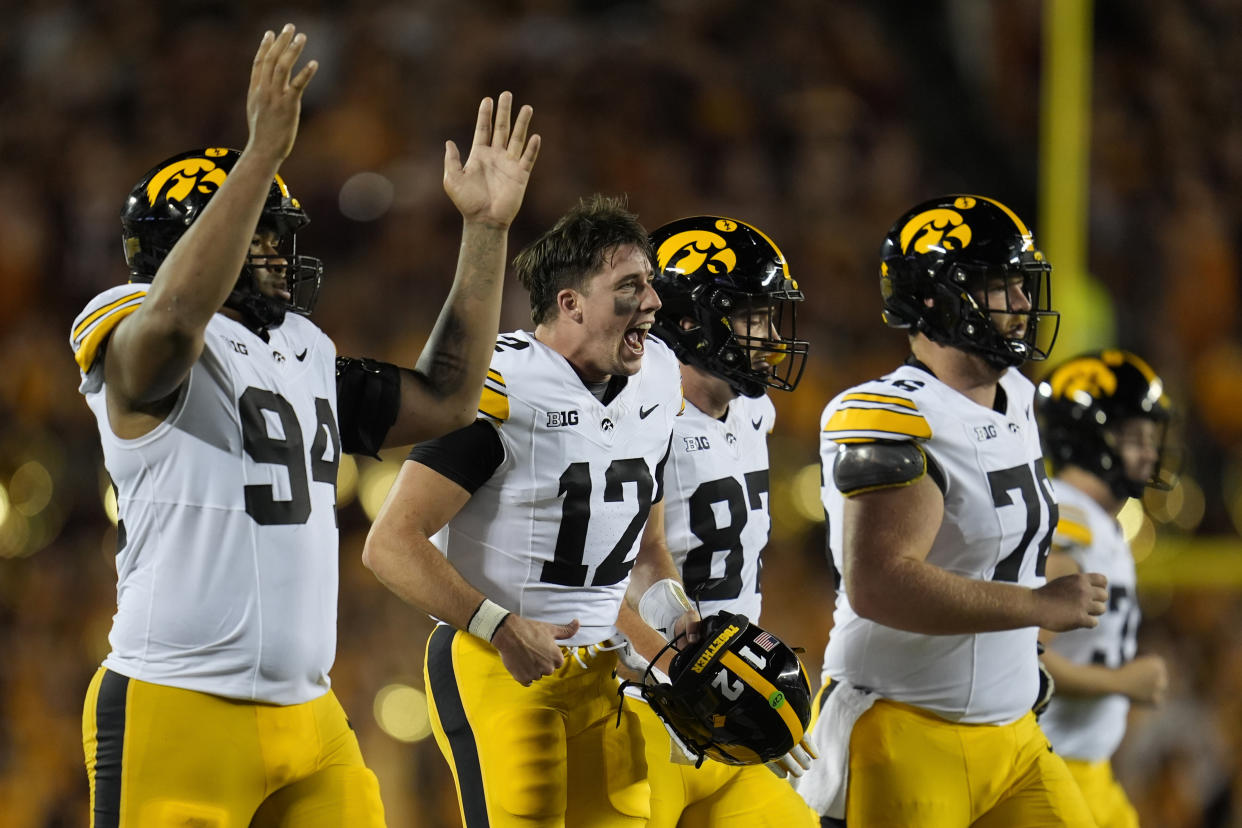 Iowa quarterback Cade McNamara (12) celebrates with teammates after a one-yard touchdown run by quarterback Brendan Sullivan during the second half of an NCAA college football game against Minnesota, Saturday, Sept. 21, 2024, in Minneapolis. (AP Photo/Abbie Parr)