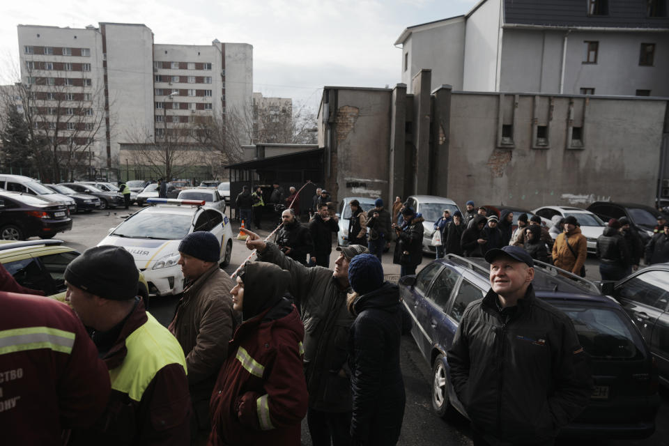 People wait behind police cordon after a rocket attack in Kyiv, Ukraine, Thursday, March 9, 2023. Russia unleashed a massive missile barrage targeting across Ukraine early Thursday, hitting residential buildings and killing an unconfirmed number of people in the largest such attack in three weeks. (AP Photo/Thibault Camus)