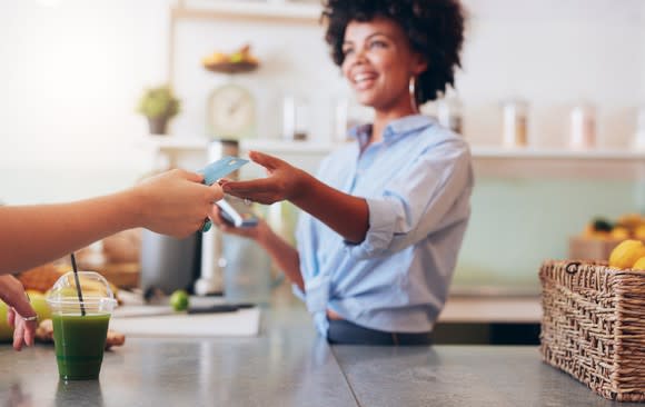 Employee accepting a credit card from customer's hand.