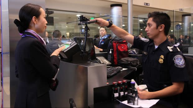 U.S Customs and Border Protection Officer Alveno Berenill takes photos of travelers as they arrive at Los Angeles International Airport on Thursday, Dec 10, 2009.
