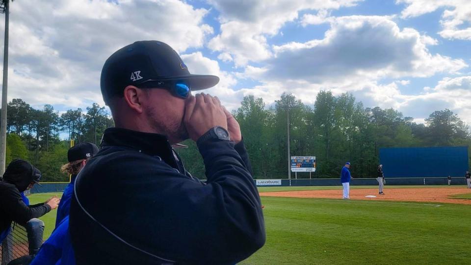 Lexington pitching coach Dell Lever covers his mouth as he signals in a pitch on a walkie-talkie device during a game against Dreher at SC Diamond Invitational. This is the first year high school baseball teams are allowed to use electronic devices to signal in pitches during games.