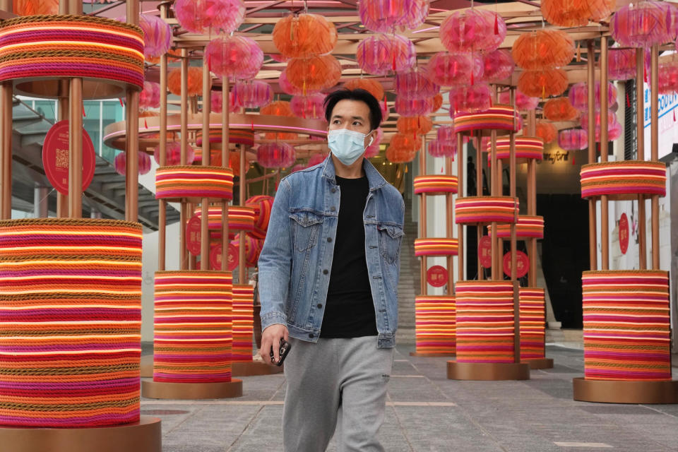 A man wearing a face mask walks along a street in Hong Kong, Friday, Jan. 28, 2022. Hong Kong is cutting the length of mandatory quarantine for people arriving from overseas from 21 to 14 days, even as the southern Chinese city battles a new surge in COVID-19 cases. (AP Photo/Kin Cheung)