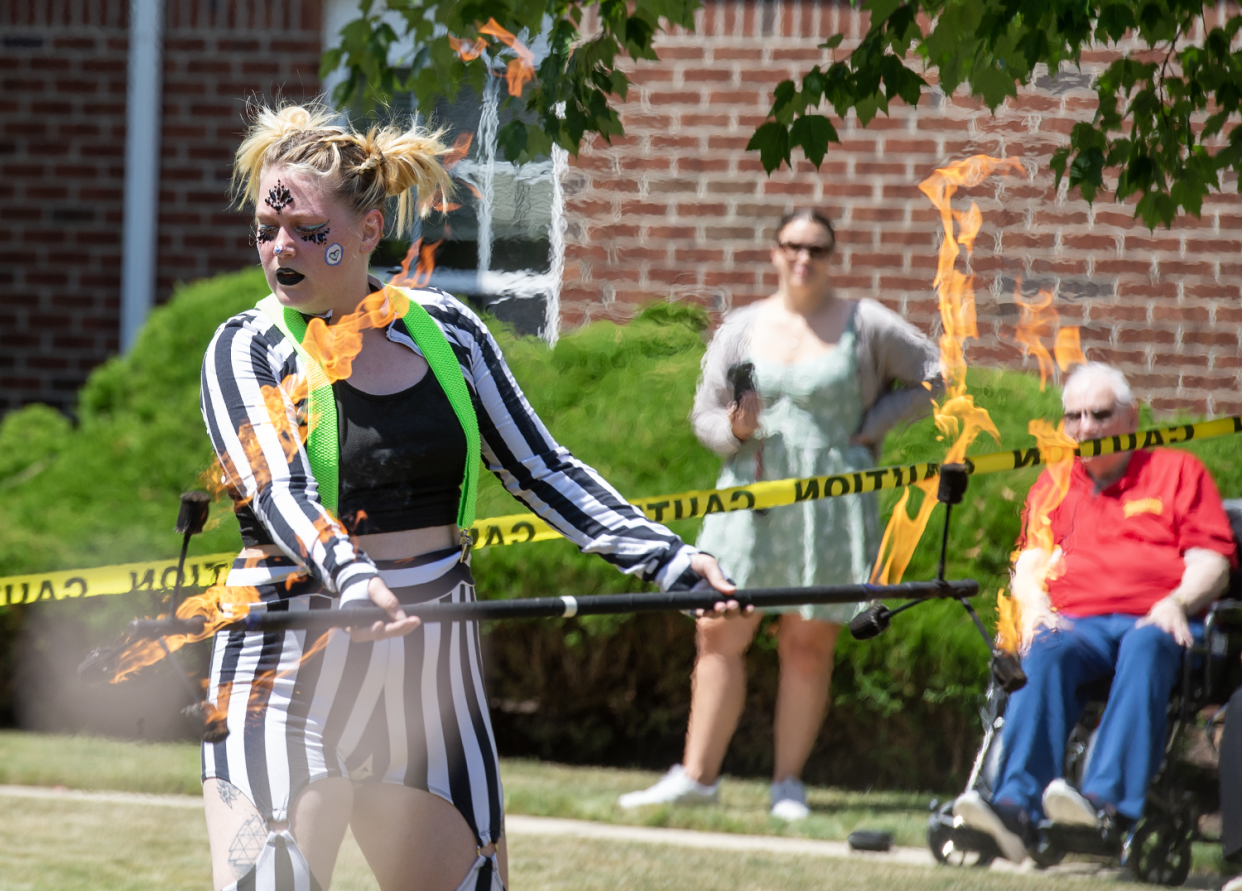 Hailey McCracken performs fire spinning as Edward Limbach, in red, watches during his circus showcase at Independence Village of Aurora on Thursday.