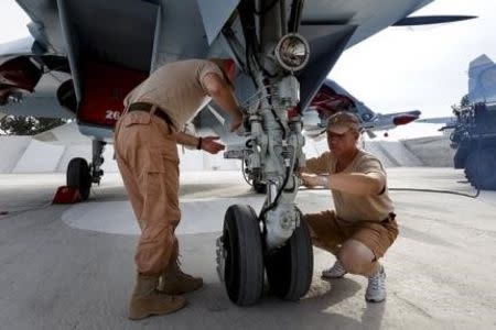 Russian ground staff members work on a Sukhoi Su-30 fighter jet at the Hmeymim air base near Latakia, Syria, in this handout photograph released by Russia's Defence Ministry October 22, 2015. REUTERS/Ministry of Defence of the Russian Federation/Handout via Reuters