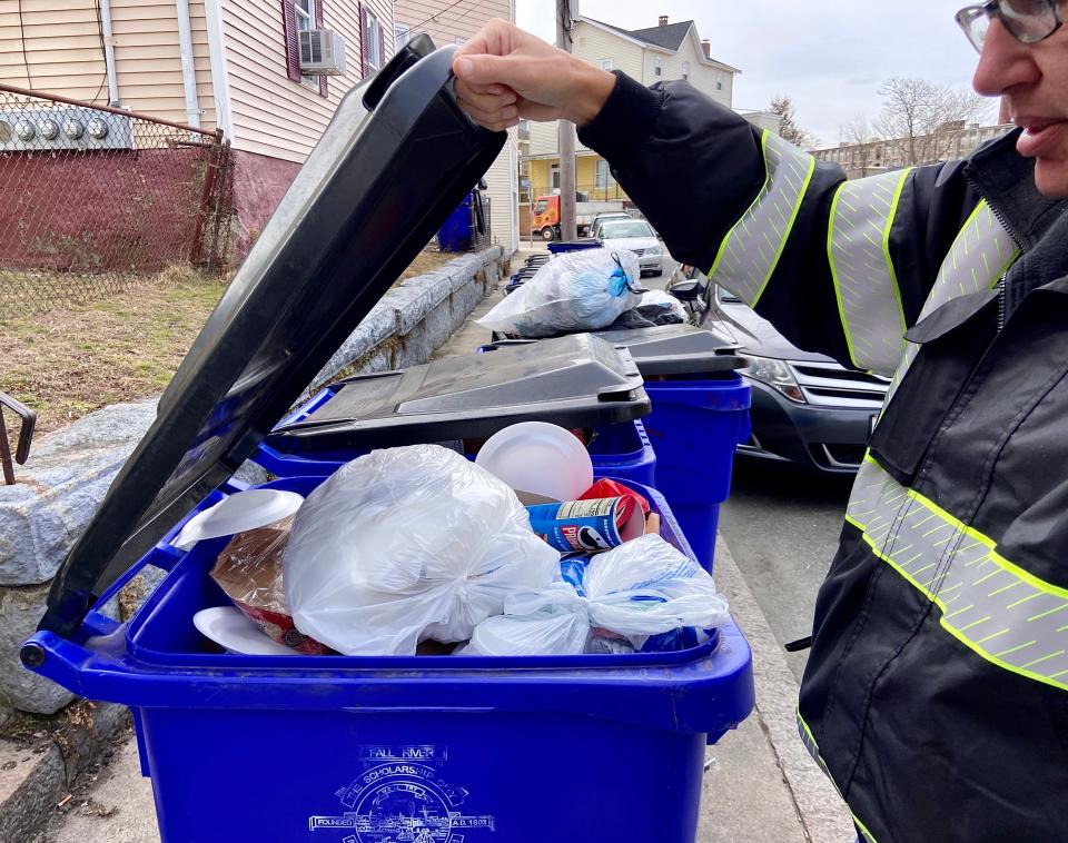 Fall River trash compliance officer foreman Charles Denmead inspects a curbside recycle bin on Rocliffe Street that is not compliant with city trash rules.