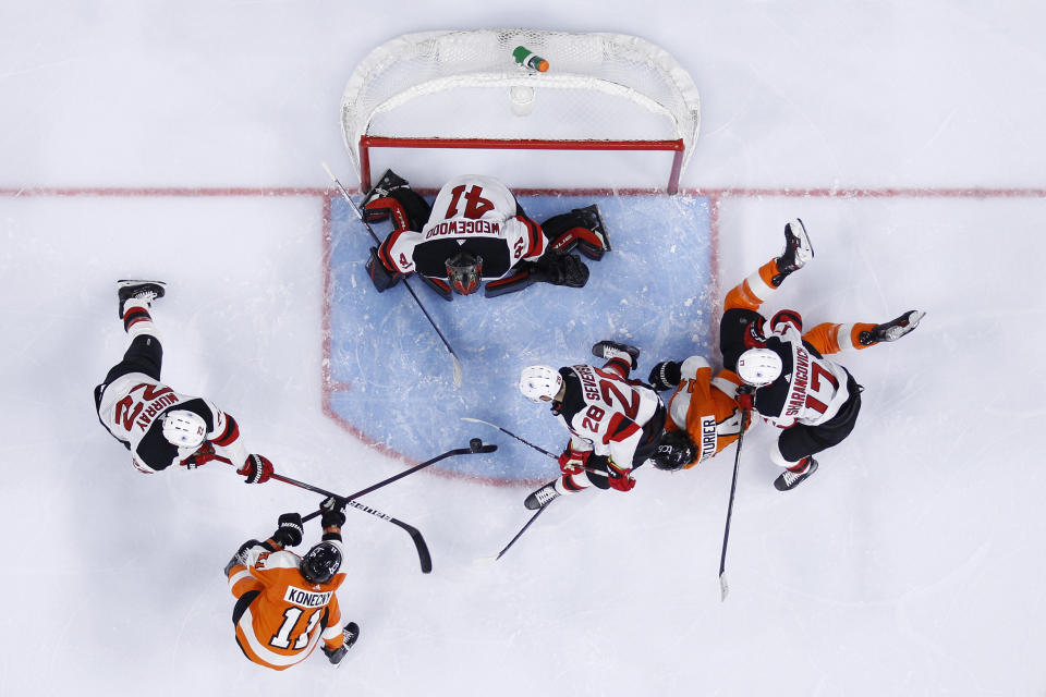 Philadelphia Flyers' Travis Konecny (11) tries to get a shot past New Jersey Devils' Scott Wedgewood (41), Ryan Murray (22) and Damon Severson (28) as Yegor Sharangovich (17) defends against Sean Couturier (14) during the second period of an NHL hockey game, Monday, May 10, 2021, in Philadelphia. (AP Photo/Matt Slocum)