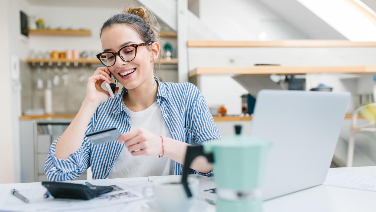 Young woman paying bills/ shopping online with credit card.