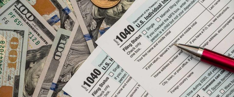 1040 US tax form with pen and dollars on desk.