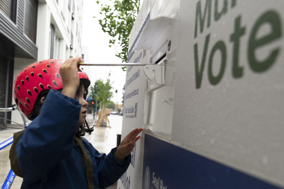FILE - Ramona McCune, puts vote-by-mail ballots into a dropbox during primary voting on May 21, 2024, in Portland, Ore. Ramona was helping their mom drop off ballots for friends. The Biden campaign is calling on the Republican National Committee and Trump campaign to drop their many lawsuits around the country targeting mail voting. (AP Photo/Jenny Kane)