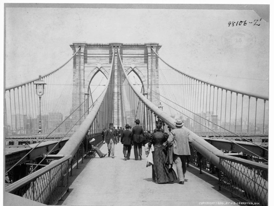 Pedestrians stroll across a walkway on the Brooklyn Bridge