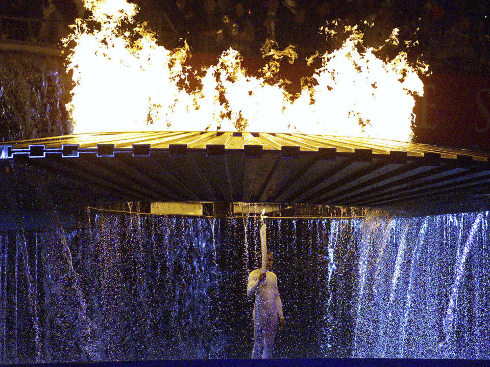 Australian runner Cathy Freeman stands under the Olympic torch after lighting the flame at the opening ceremonies for the 2000 Summer Olympics in Sydney, Australia, Sept. 15, 2000. (AP Photo/Kevin Frayer)