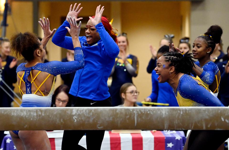 Fisk University gymnast Aliyah Reed-Hammon, left, celebrates with Zyia Coleman and Naimah Muhammad, right, after she finished her routine on the balance beam  during the Tennessee Collegiate Classic meet Friday, Jan. 20, 2023, in Lebanon, Tenn. Fisk is the first historically Black university to have an intercollegiate women’s gymnastics team.