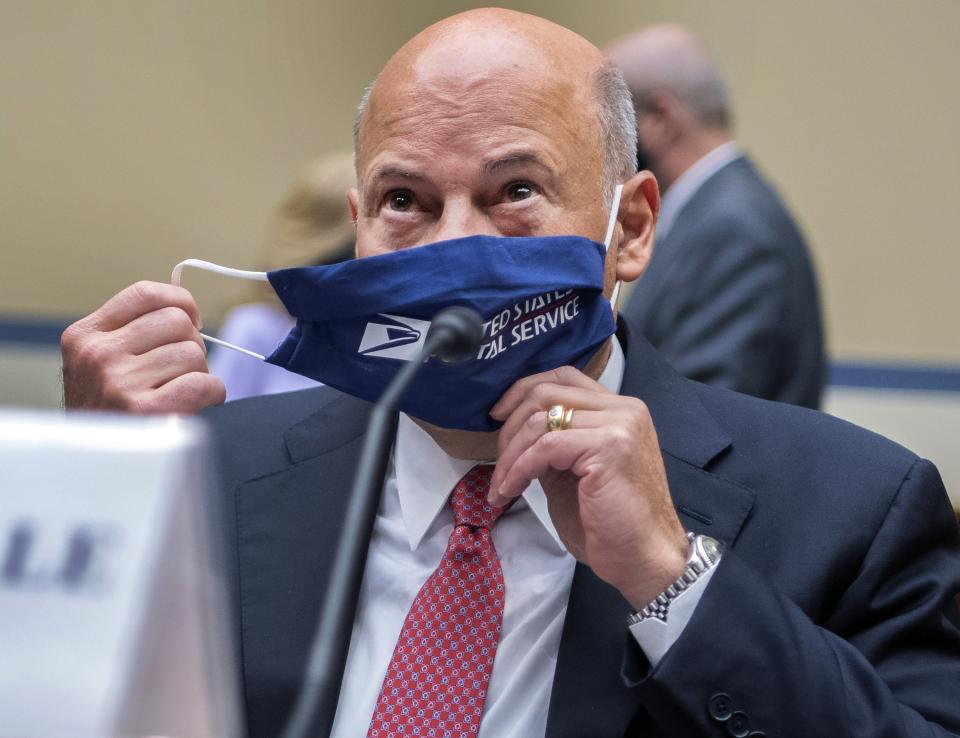 FILE - In this Aug. 24, 2020, file photo, Postmaster General Louis DeJoy removes his face mask as he arrives to testify before a House Oversight and Reform Committee hearing on the Postal Service on Capitol Hill in Washington. The U.S. Postal Service agreed Wednesday, Oct. 14, to reverse changes that slowed mail service nationwide, settling a lawsuit filed by Montana Gov. Steve Bullock during a pandemic that is expected to force many more people to vote by mail. (Tom Williams/Pool Photo via AP, File)