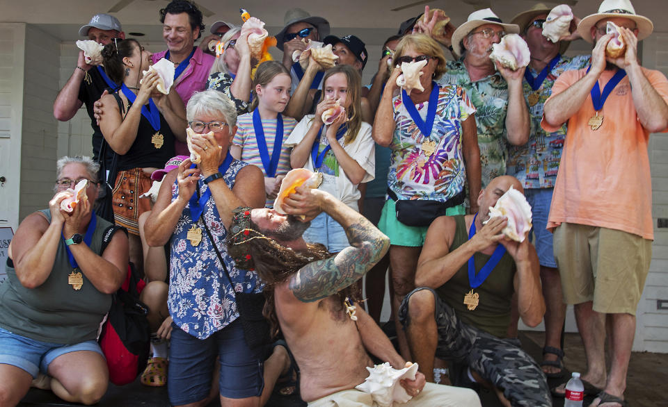 In this photo provided by the Florida Keys News Bureau, contestants in the Conch Shell Blowing Contest toot their "horns," Saturday, March 4, 2023, in Key West, Fla. Organized by the Old Island Restoration Foundation, the event is a Key West tradition that began in 1972. The conch shell is a symbol of the Florida Keys. (Mary Martin/Florida Keys News Bureau via AP)