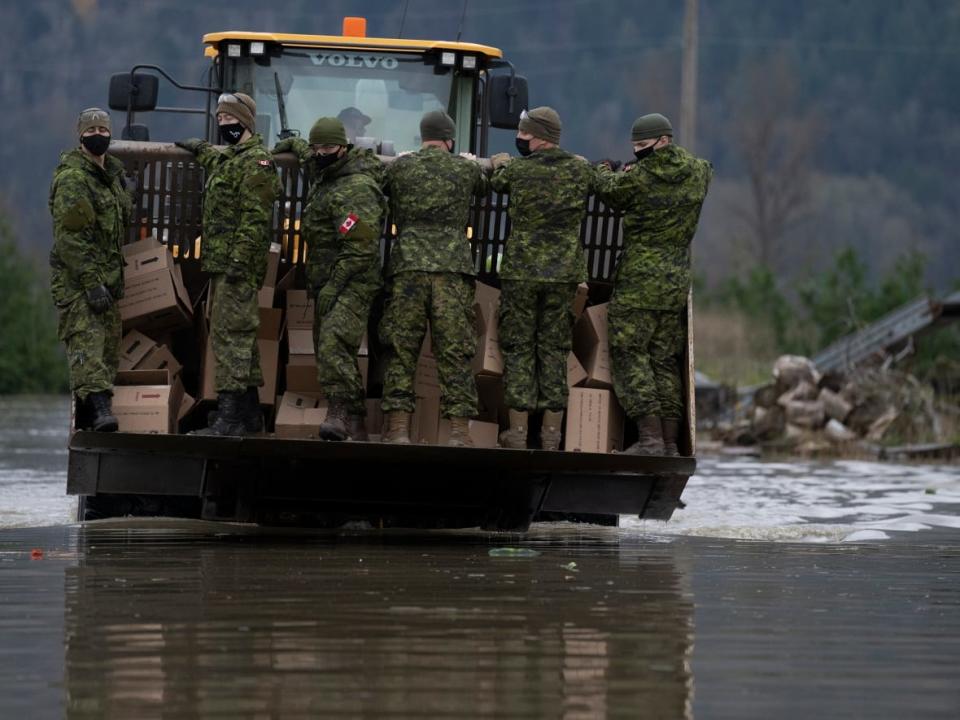 Members of the Canadian Forces arrive by front end loader to help residents cope with catastrophic flooding in Abbotsford, B.C. on November 20, 2021. Climate-driven weather events are part of the array of new threats Canada needs to incorporate into its national security strategy, experts say. (THE CANADIAN PRESS/Jonathan Hayward - image credit)