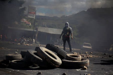 A supporter of Salvador Nasralla, presidential candidate for the Opposition Alliance Against the Dictatorship, stands near a burning barricade settled to block road during a protest caused by the delayed vote count for the presidential election in Tegucigalpa, Honduras December 1, 2017. REUTERS/Jorge Cabrera