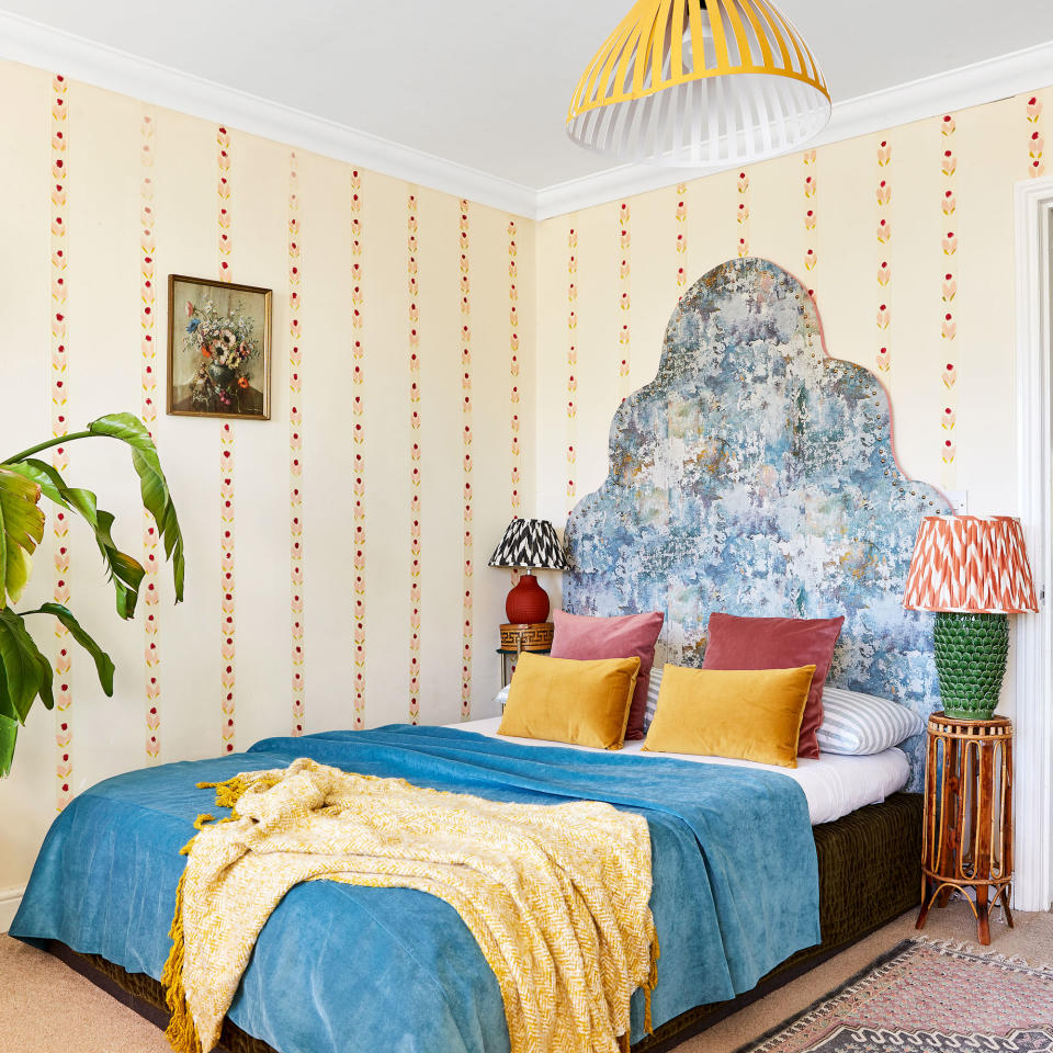 Bedroom with statement handmade and upholstered headboard and hand-painted pattern on walls