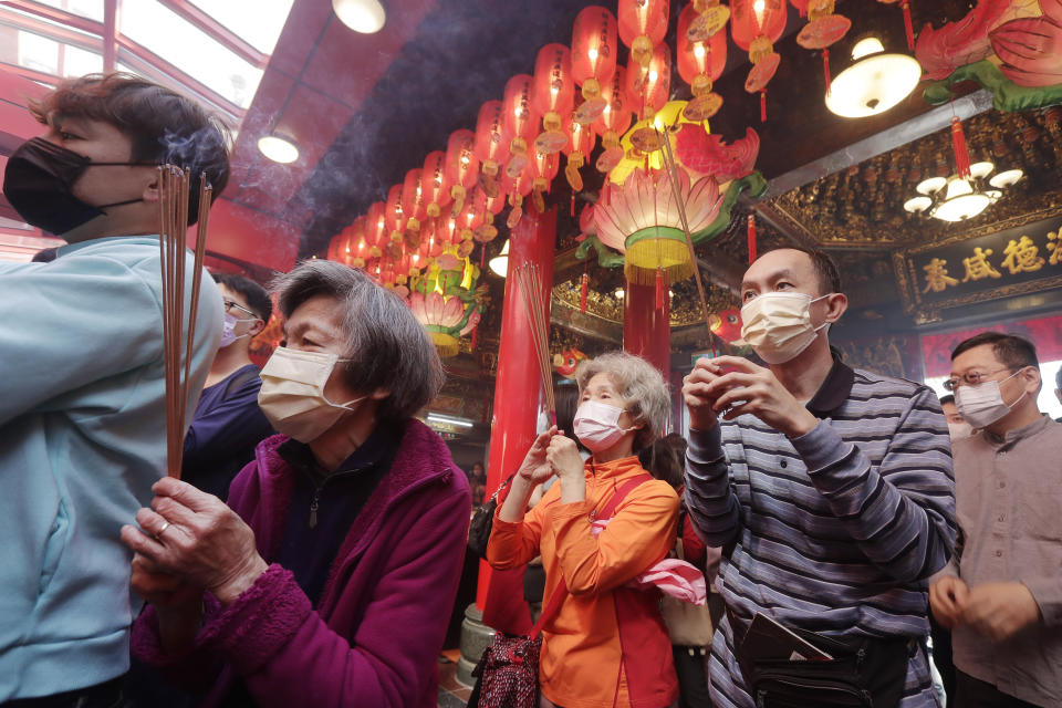 FILE - Worshippers wearing face masks pray at a temple on the first day of the Chinese Lunar New Year, the Year of the Rabbit, in Taipei, Taiwan, on Jan. 22, 2023. While polls show most people on the island reject reunification, many say they are attracted to their much larger neighbor’s dynamic economy, and its shared language and culture. Others are simply numb to hearing about the threat in their backyard. (AP Photo/Chiang Ying-ying, File)