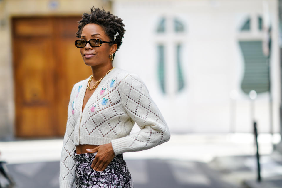 PARIS, FRANCE - AUGUST 26: Ellie Delphine wears pearl beaded hair pins, golden earrings, a golden chain necklace, a white wool floral print cropped cardigan from Alessandra Rich, on August 26, 2020 in Paris, France. (Photo by Edward Berthelot/Getty Images)