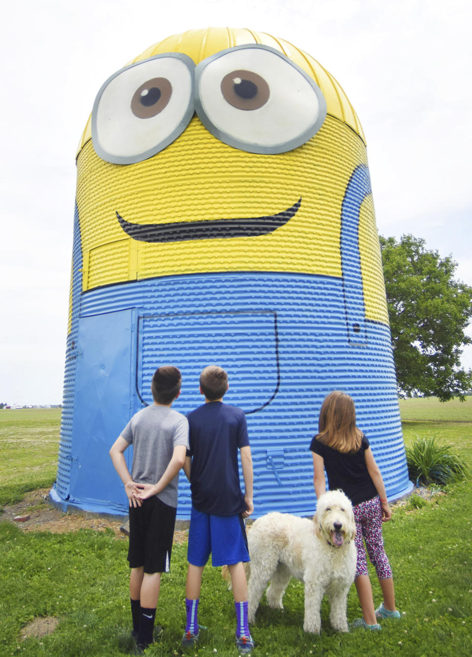 FILE - Kids peer up at a silo painted like a minion in Ossian, Ind., on June 9, 2016. This summer, the goggle-wearing yellow ones will return in “Minions: Rise of Gru," in theaters July 1. The “Despicable Me” franchise and its “Minions” spinoffs are the highest grossing animated film franchise ever with more than $3.7 billion in tickets sold worldwide. (Rachel Von /The Journal-Gazette via AP, File)