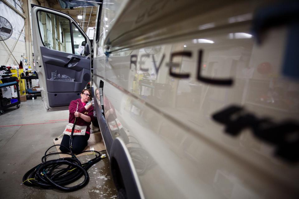 Workers install a wiring harness on a Winnebago Revel camper van at the company's Lake Mills factory.