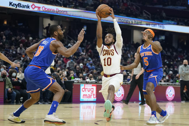 Cleveland Cavaliers' Darius Garland (10) drives between New York Knicks' Alec Burks (18) and Immanuel Quickley (5) in the first half of an NBA basketball game, Monday, Jan. 24, 2022, in Cleveland. (AP Photo/Tony Dejak)