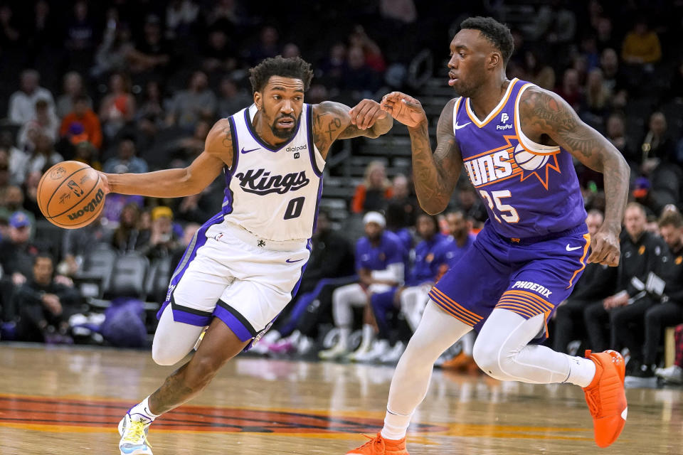 Sacramento Kings' Malik Monk (0) drives around against Phoenix Suns' Nassir Little (25) during the first half of an NBA basketball game Friday, Dec. 8, 2023, in Phoenix. (AP Photo/Darryl Webb)