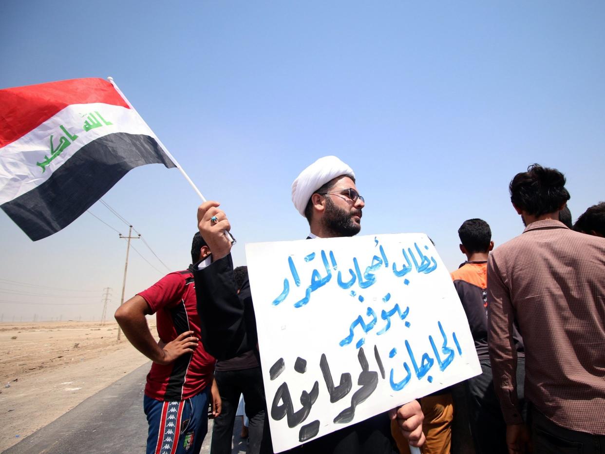 A protester holds a sign that reads "We ask the decision makers to provide the things we are deprived of" during a protest in south of Basra, 16 July: Reuters