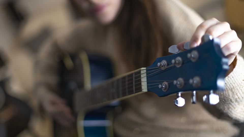 Woman tuning guitar