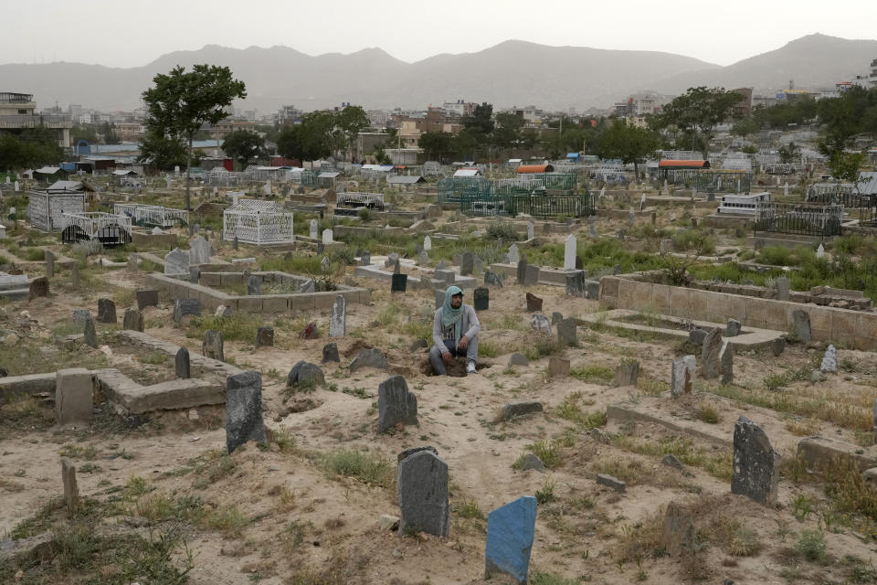An Afghan sits on a grave at a cemetery in Kabul, Afghanistan, Sunday, May 15, 2022. There are cemeteries all over Afghanistan's capital, Kabul, many of them filled with the dead from the country's decades of war. They are incorporated casually into Afghans' lives. They provide open spaces where children play football or cricket or fly kites, where adults hang out, smoking, talking and joking, since there are few public parks. (AP Photo/Ebrahim Noroozi)