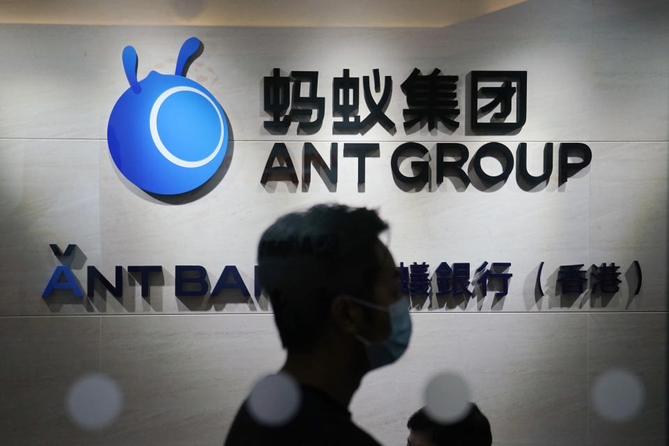 In this Friday, Oct. 23, 2020, photo, an employee walks past a logo of the Ant Group at their office in Hong Kong. The world's largest fintech company, China's Ant Group, will try to raise nearly $35 billion in a massive public offering of stock that would shatter records. (AP Photo/Kin Cheung)