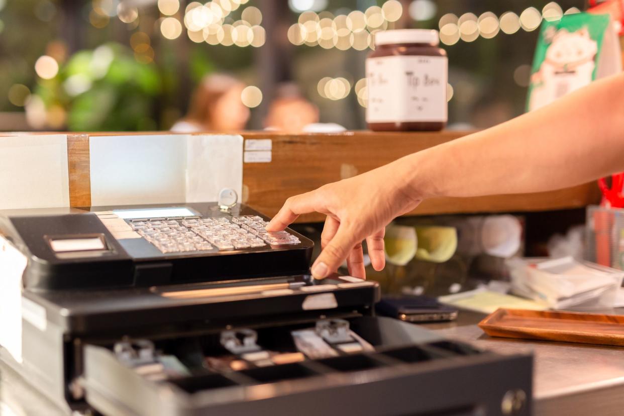 Shot in low light hand pressing electronic cash register in a shop